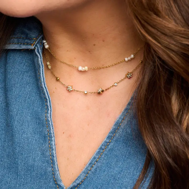 Marina freshwater pearl necklace worn with a longer gold-tone necklace and an open-neck denim shirt.