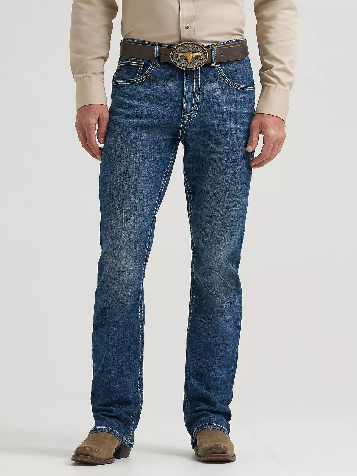 Person wearing blue jeans with a brown belt and tan shirt on a white background