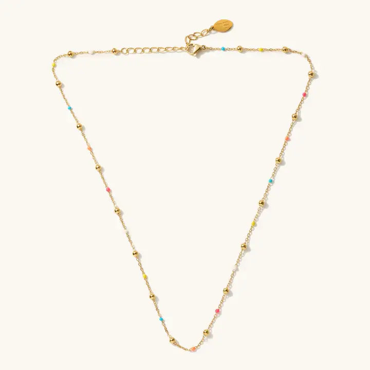Phoebe gold-tone ball necklace with tiny multicolored beads and an extender, laid flat on a light background.