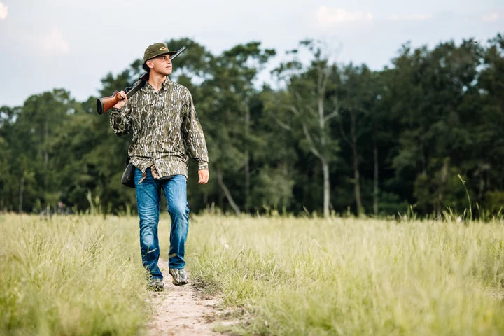 Drake 8 Shot Flyweight long-sleeve shirt in Bottomland camo, worn by man walking a field path