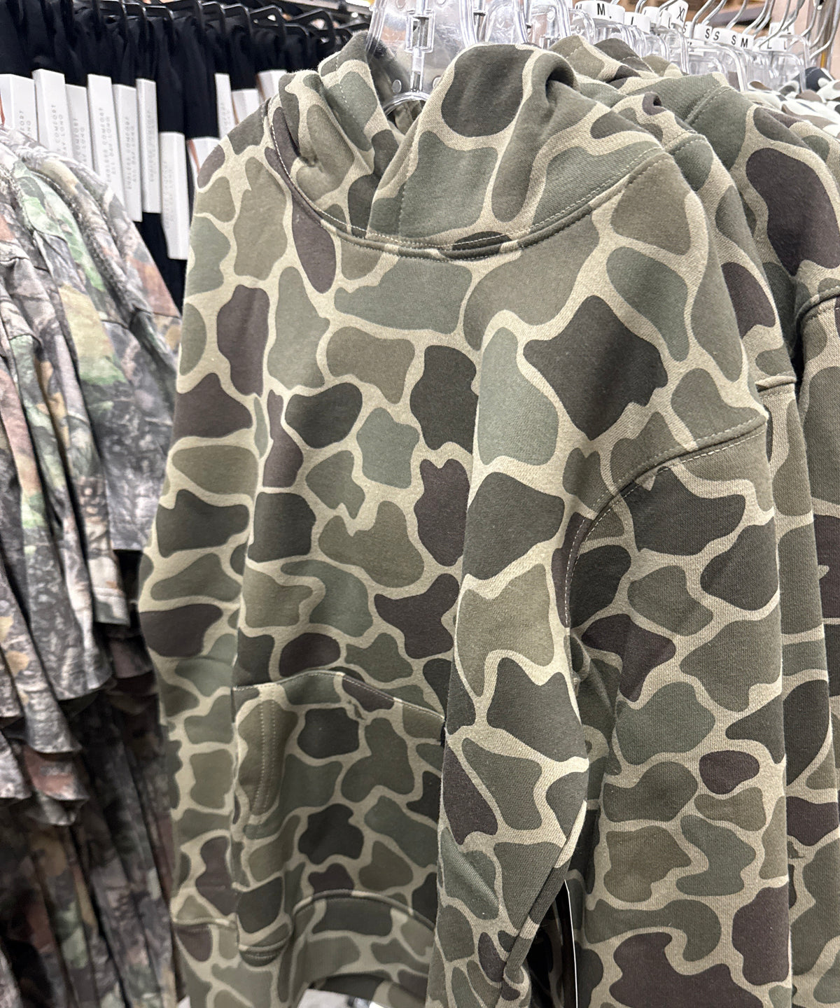 Local Boy Youth Hilltop Camo Hoodies in green camo hanging on a store rack
