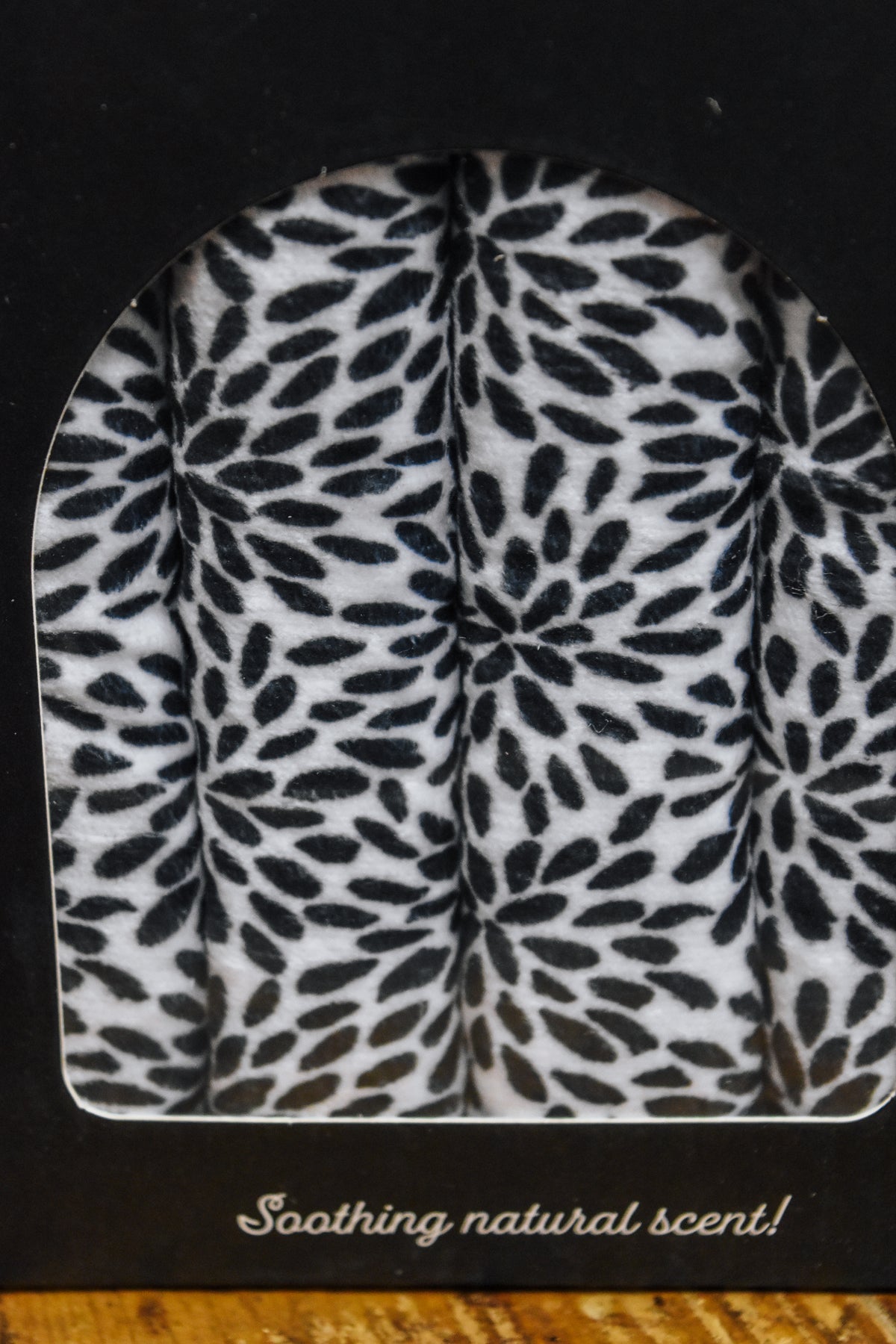 Hot Stuff Heated Neck Wrap in black and white, close-up of the leaf print through the box window
