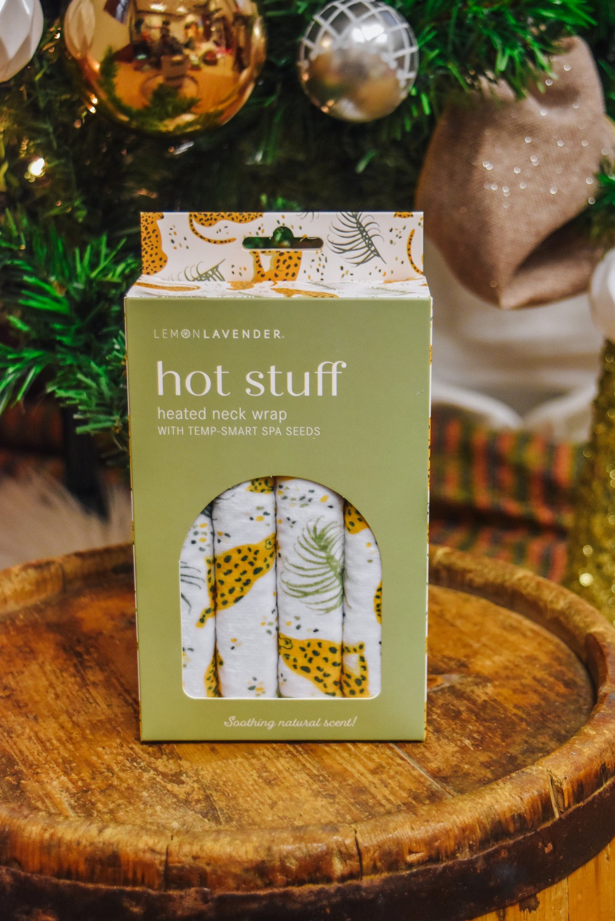 Lemon Lavender Hot Stuff Heated Neck Wrap in cheetah print, boxed by a Christmas tree
