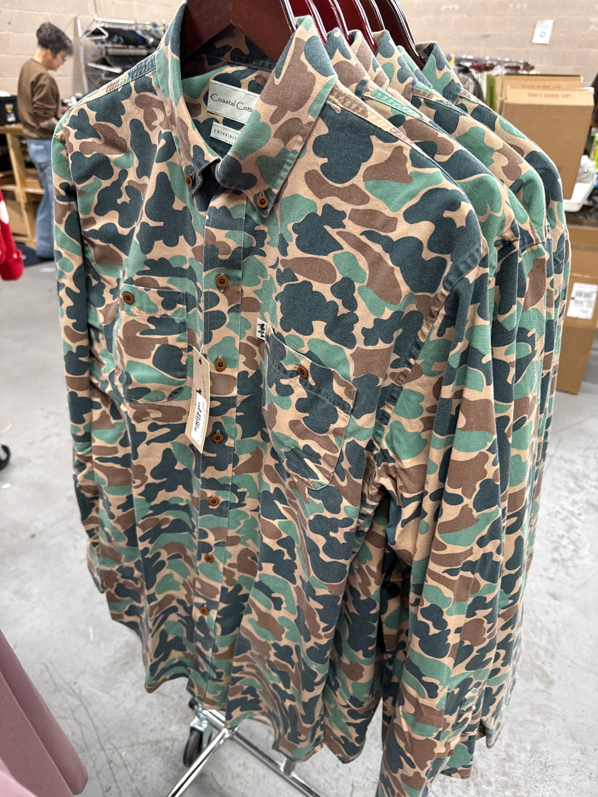 Coastal Cotton men's twill camo long sleeve shirts hanging on a store rack
