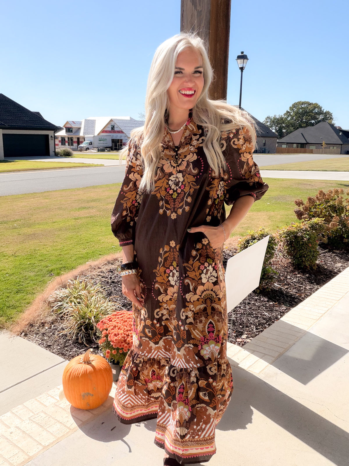 Model with hand in side pocket wearing a brown border floral print puff sleeve midi dress