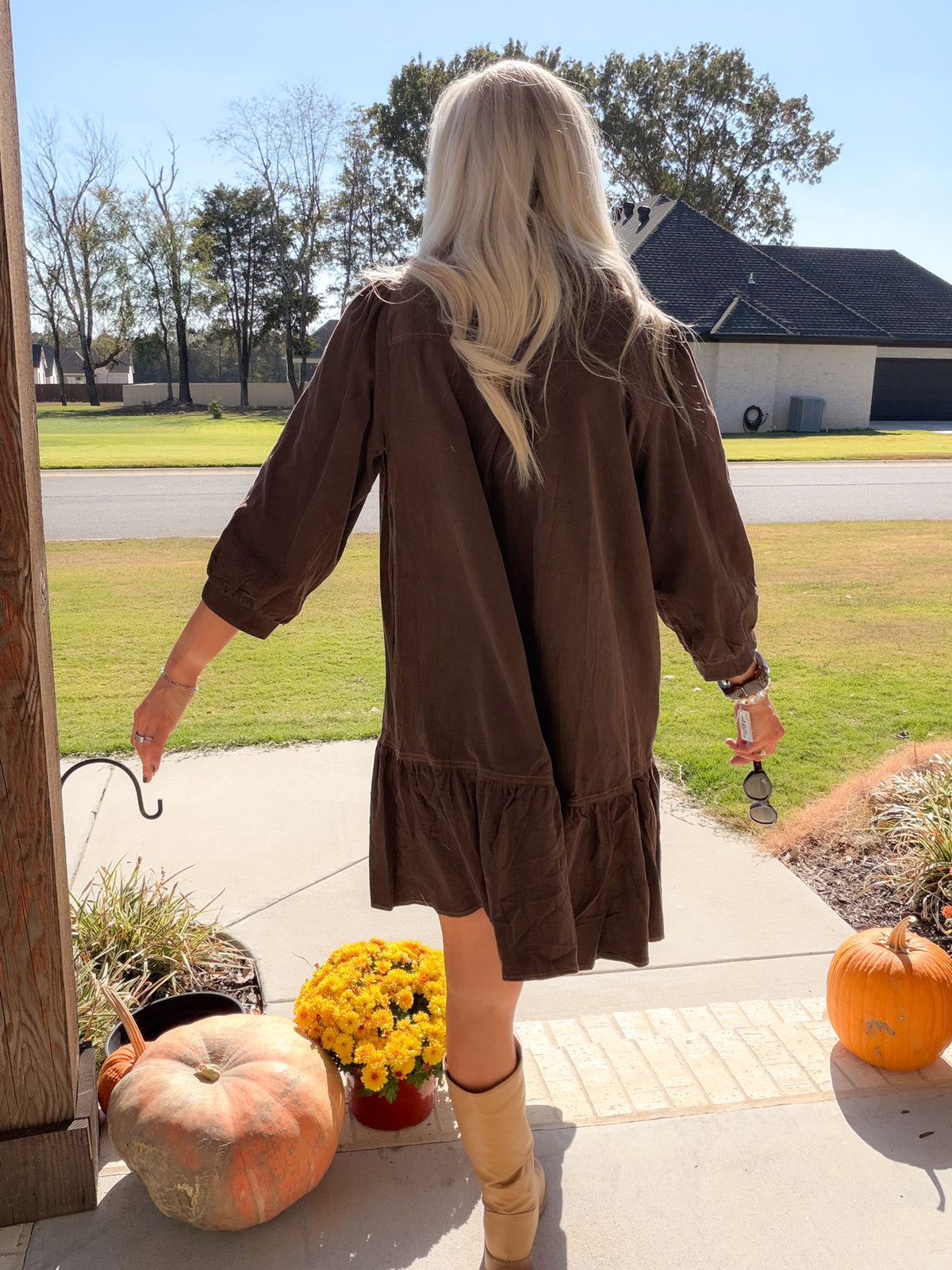 Back view of chocolate brown corduroy dress showing easy silhouette, puff sleeves, and tiered ruffle hem