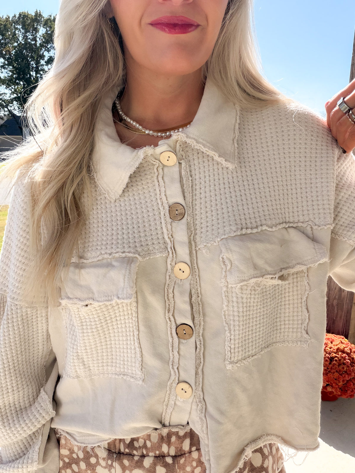 Close-up of the natural shacket's waffle-textured panels, chest pockets, round buttons, and raw-edge seams.