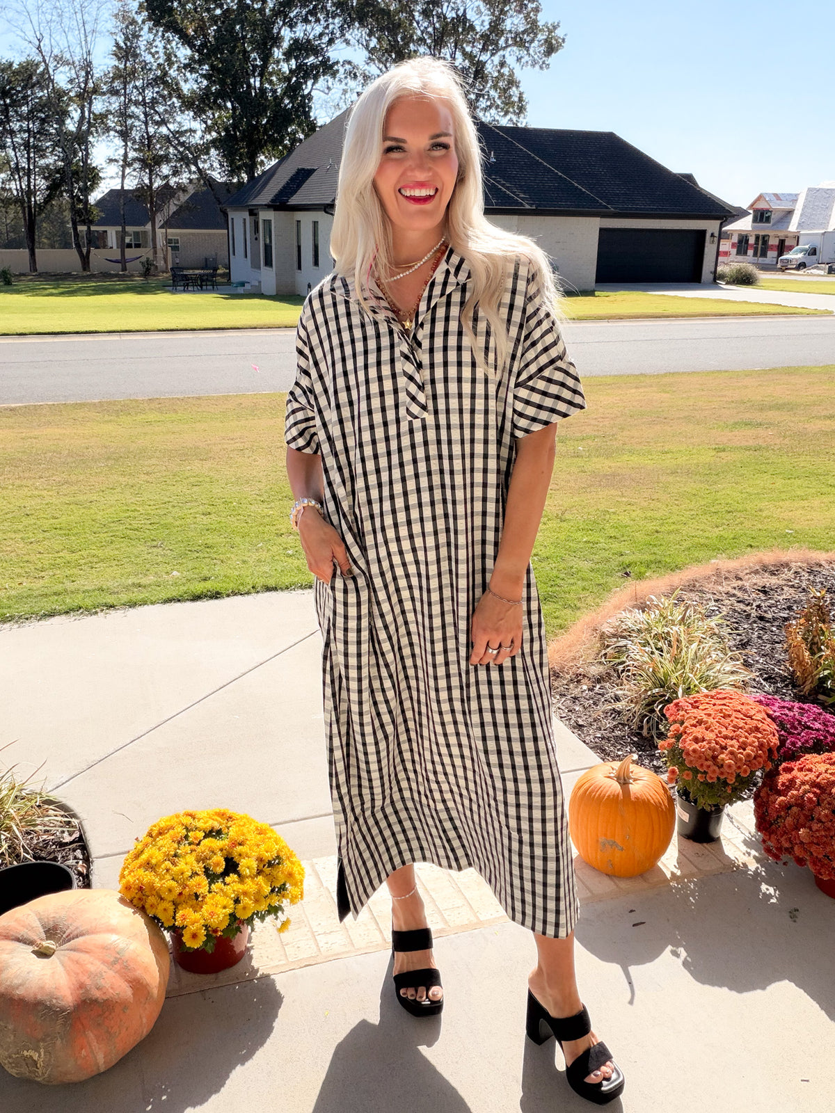 Front view of the black-and-white gingham midi dress with the model's hand in a side pocket.