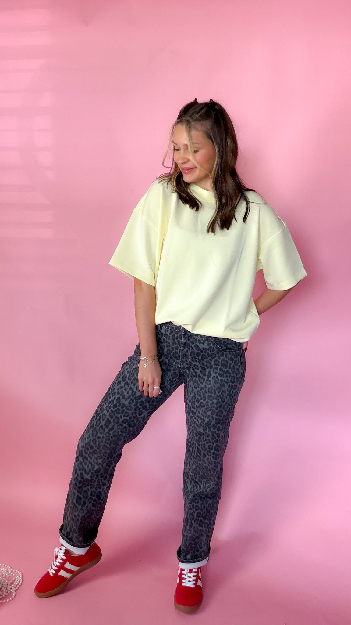 woman standing against pink background showcasing the women's silver leopard jeans