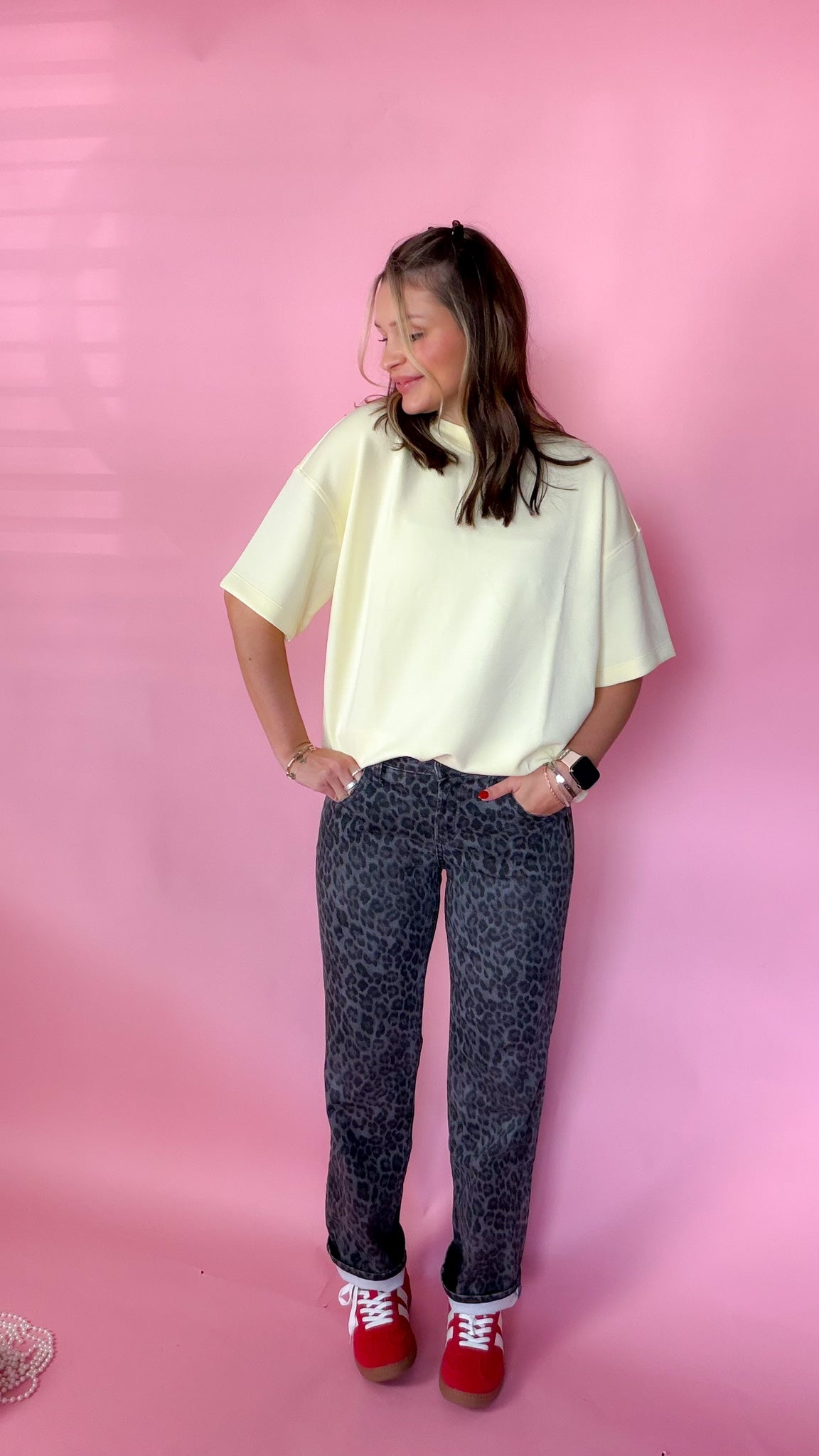 woman standing against pink background showcasing the women's silver leopard jeans