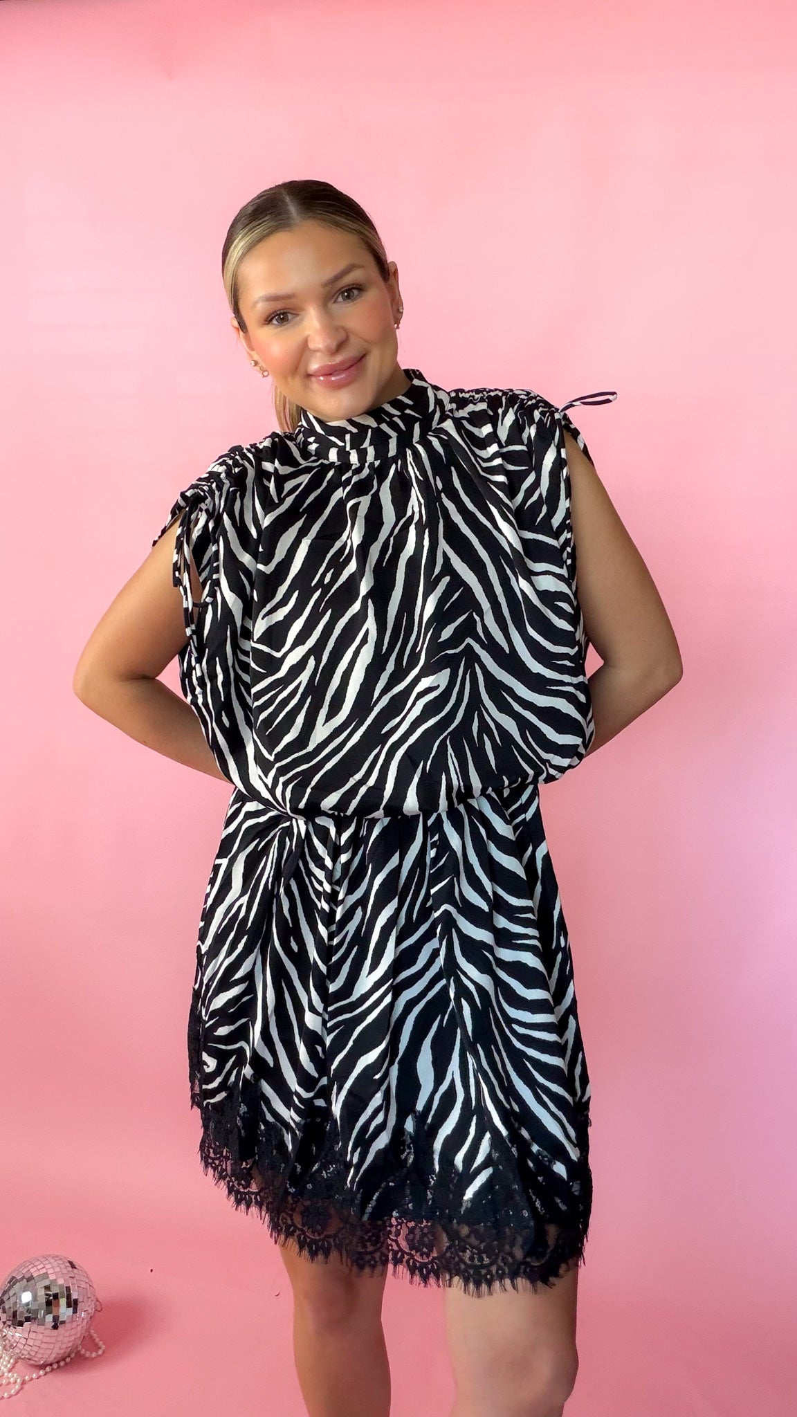 woman standing against pink background modeling the black zebra romper