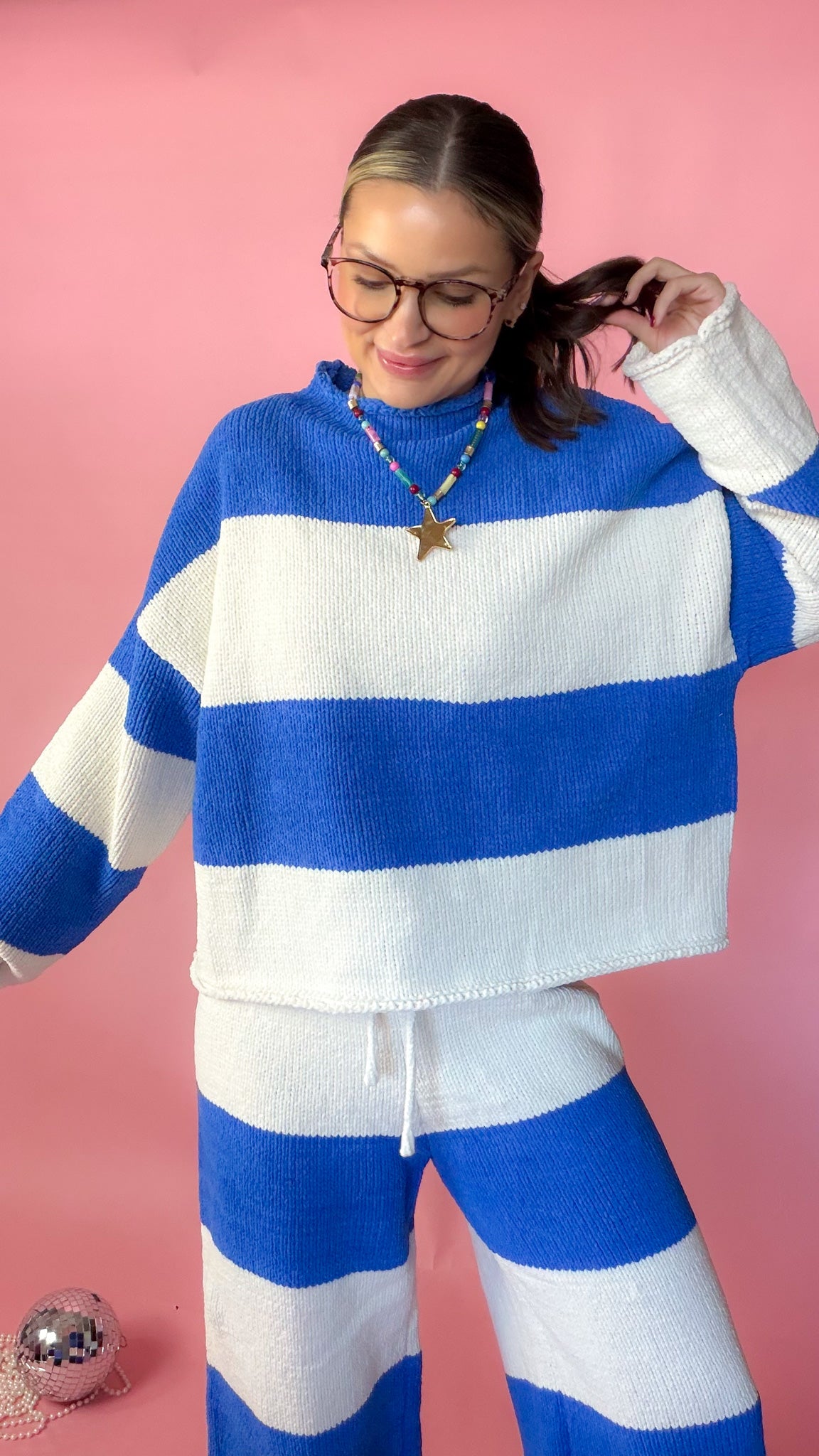 woman wearing blue stripe knit sweater against pink background