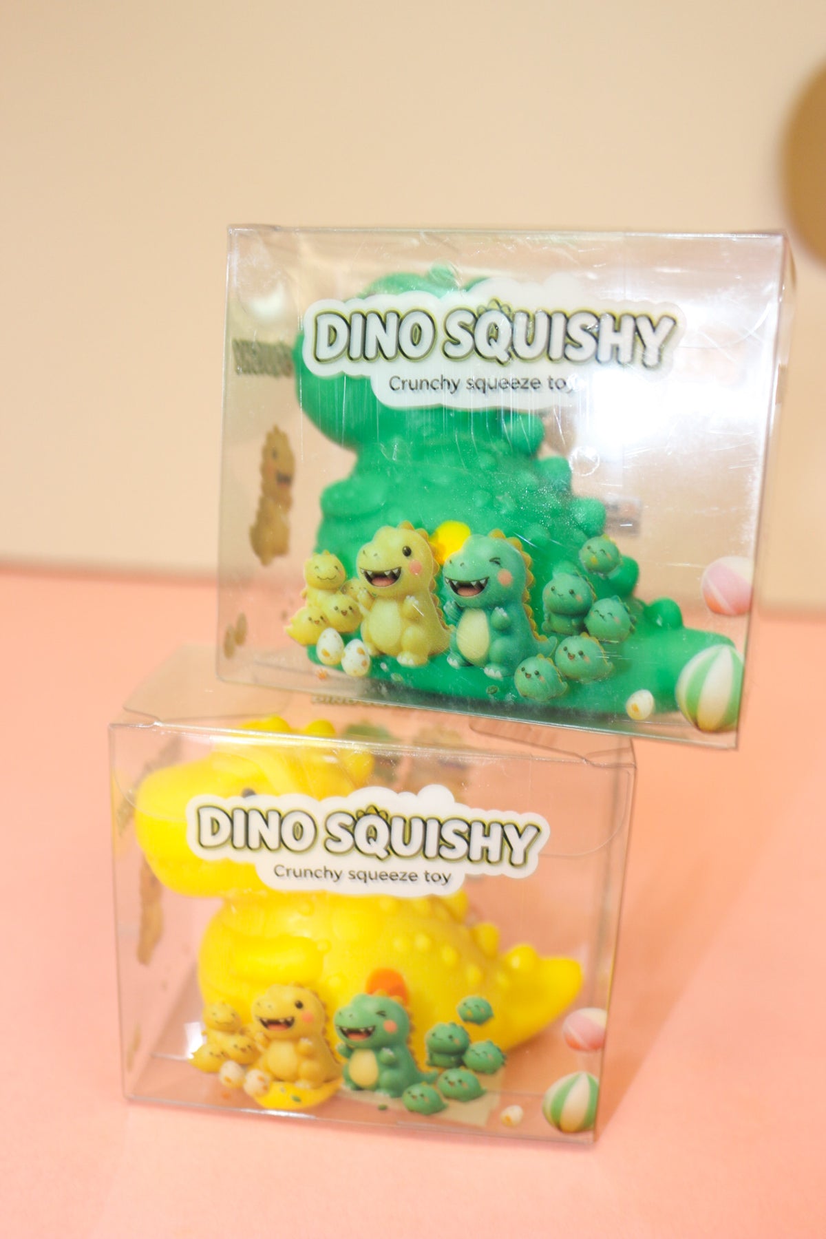 Close-up of boxed green and yellow crunchy dinosaur squeeze toys with illustrated dinosaur packaging.