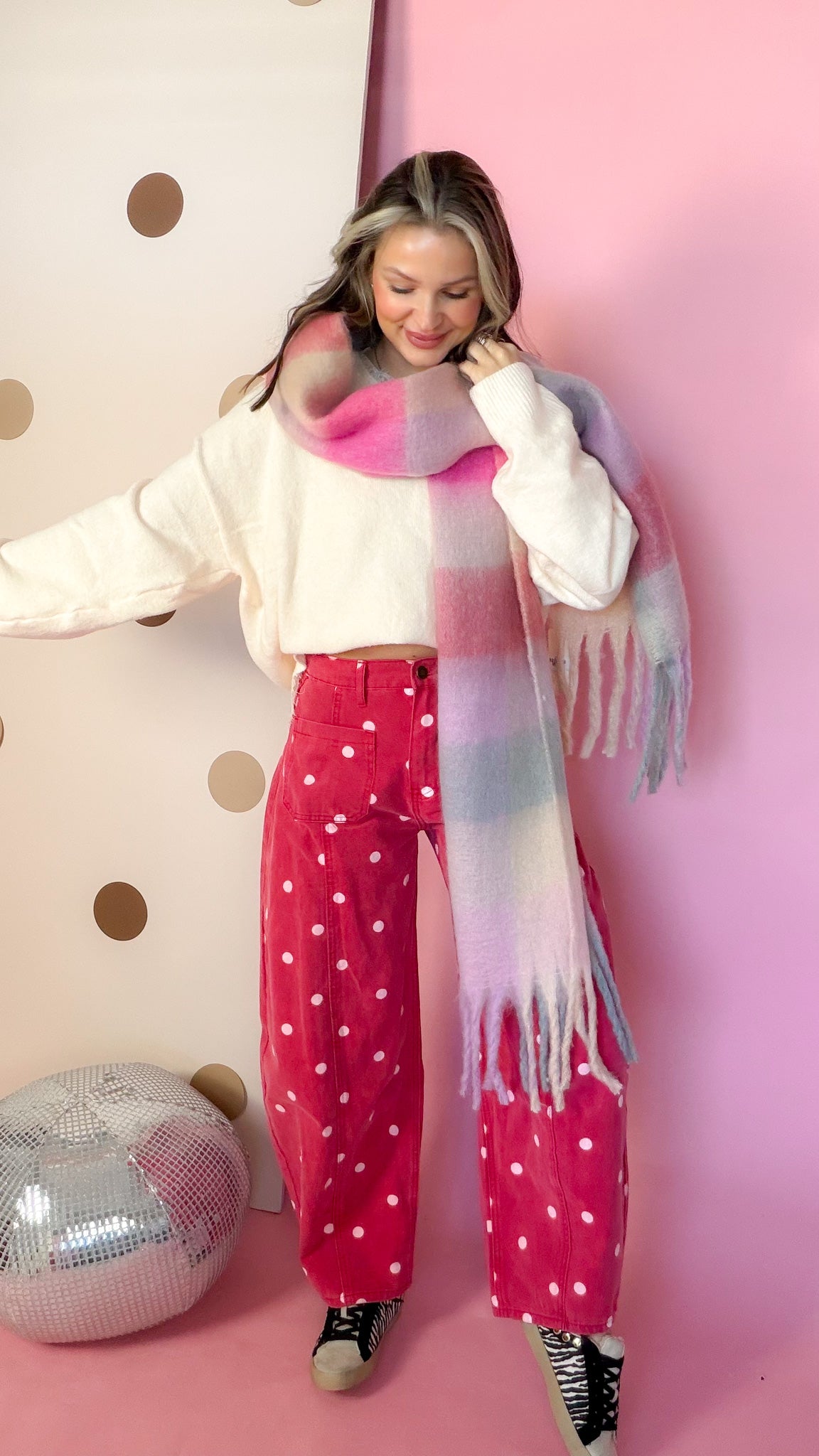 Brick red polka dot barrel jeans styled with a cream sweater and plaid scarf, full-length front view