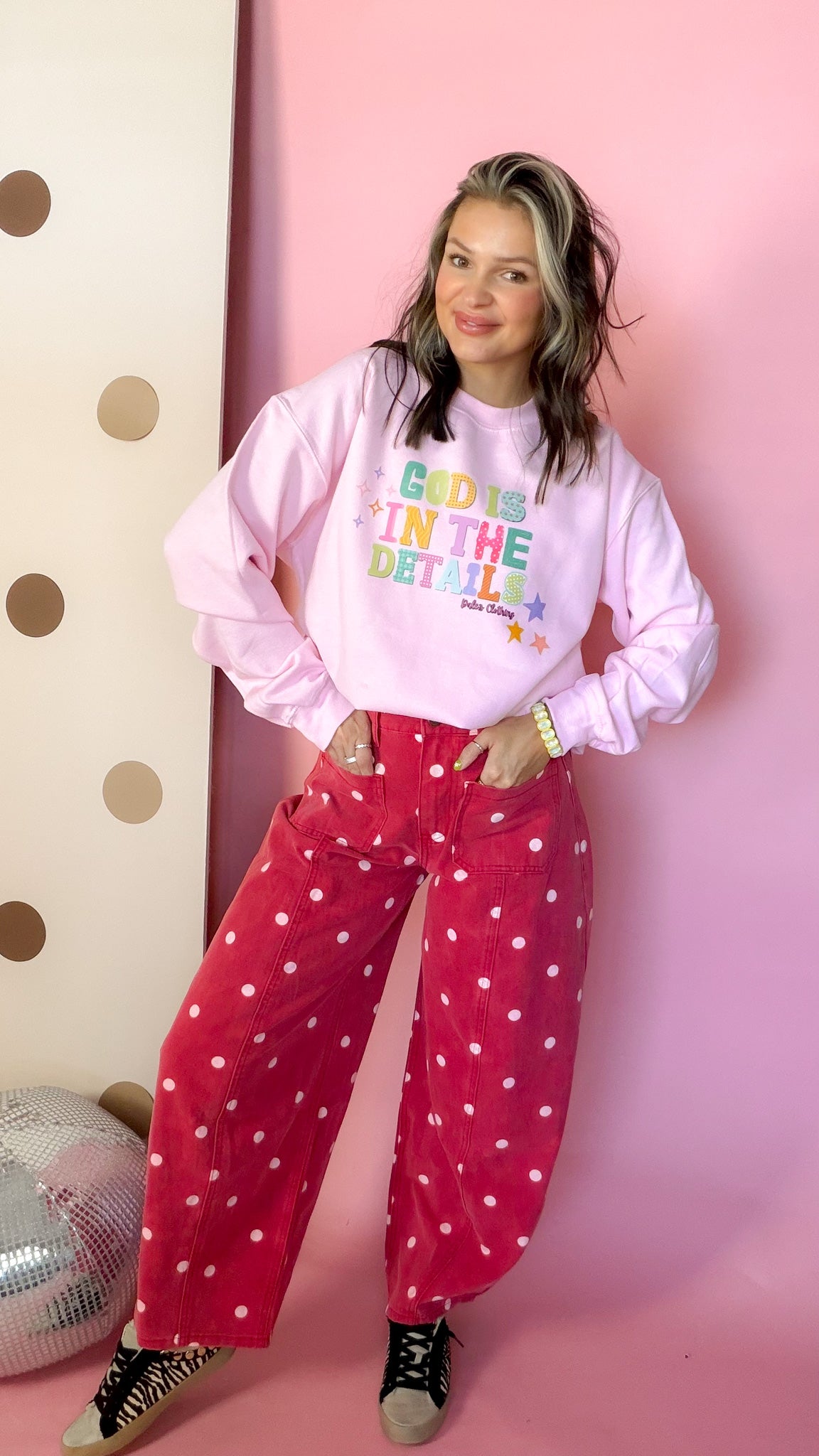 God Is In The Details pink sweatshirt, front with hands in pockets