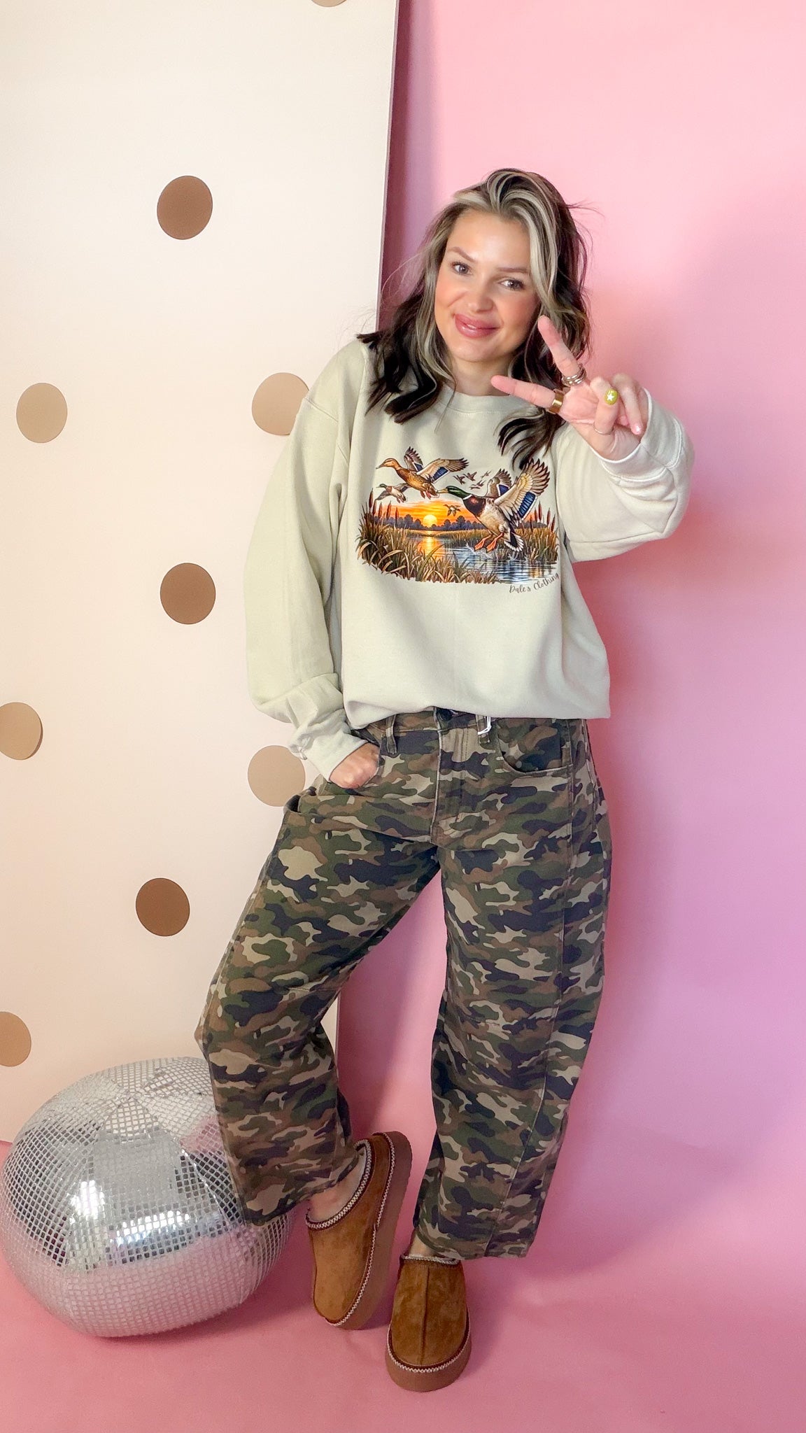 Entire Duck Crew sand sweatshirt, model giving a peace sign