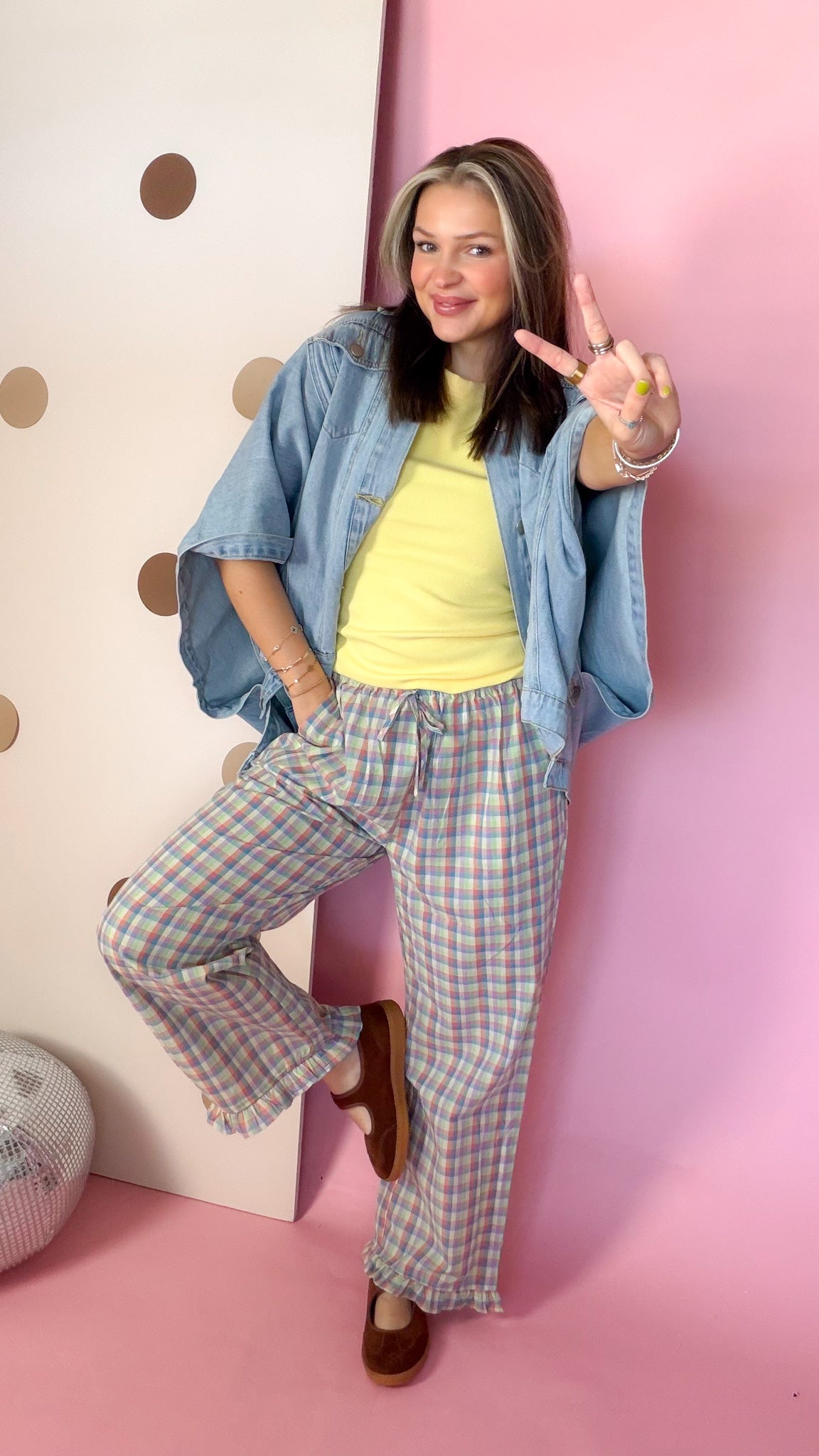 Women's yellow ribbed knit tank with denim shirt and plaid pants, model posing with one leg raised.