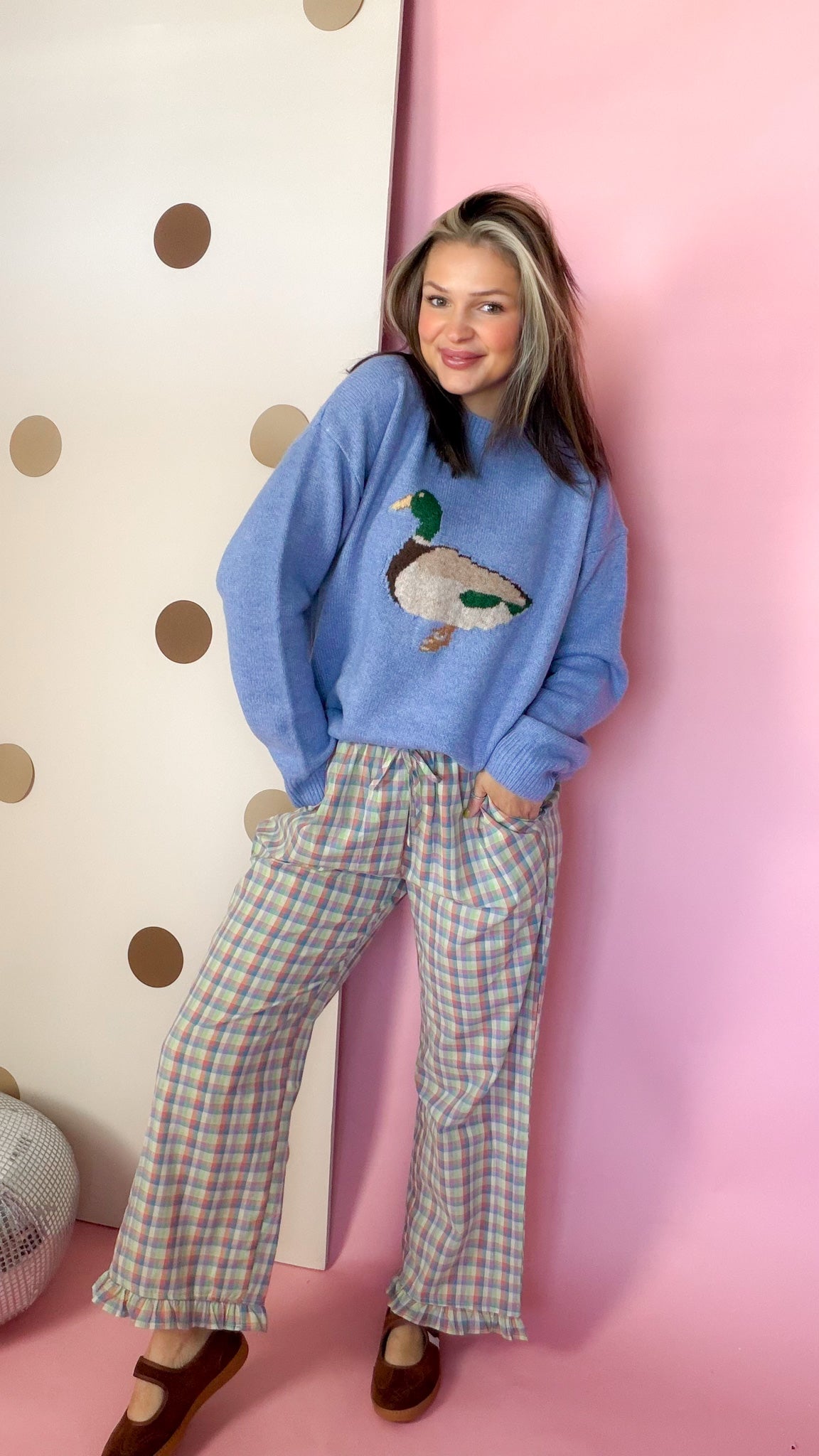 Coastal blue women's duck sweater styled with plaid pants and brown Mary Jane flats, front view.