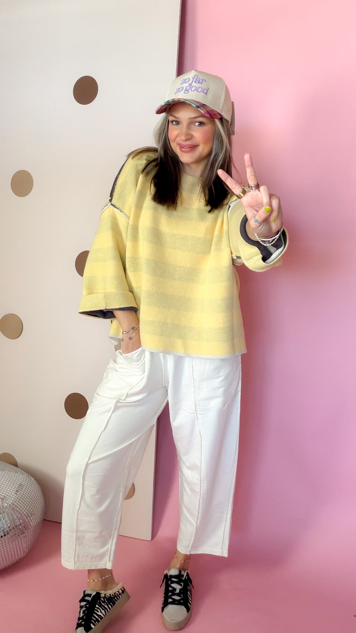 Ecru cotton barrel pants styled with a yellow plaid top, baseball cap and printed sneakers.