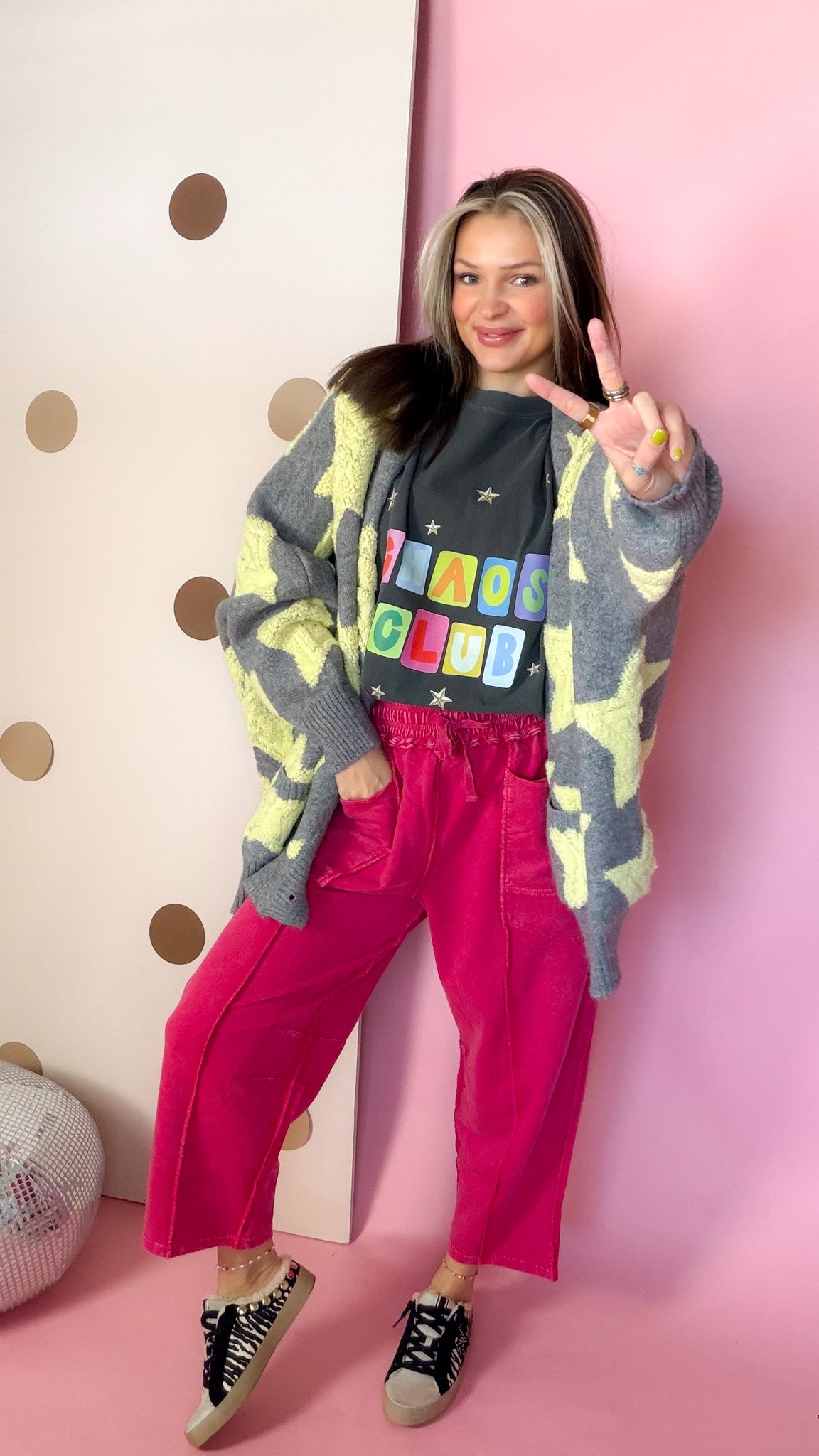 Red cotton barrel pants with exposed front seams, styled with a gray star cardigan and low-top sneakers.
