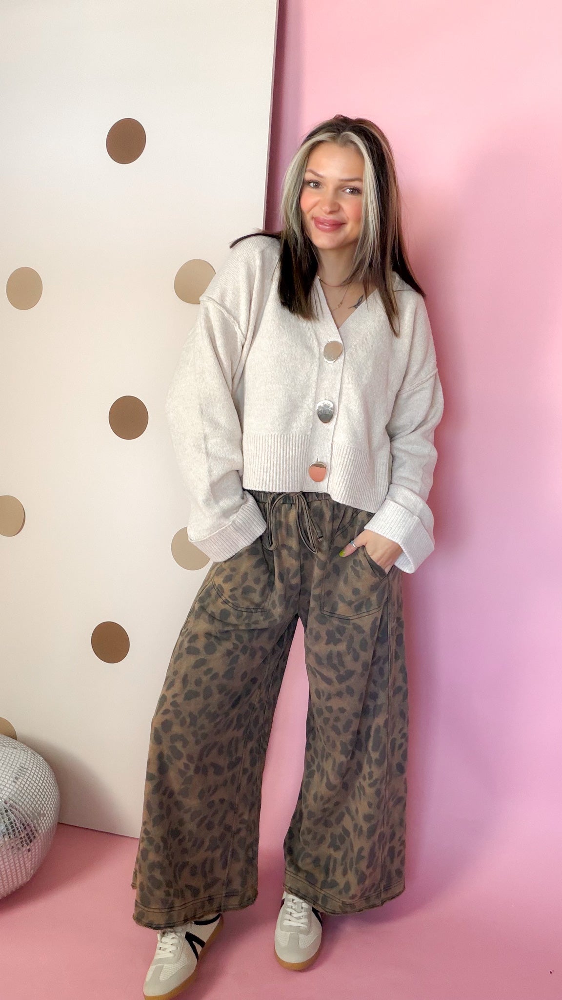 Mocha leopard wide leg pants styled with a cream cropped cardigan and sneakers, front view.