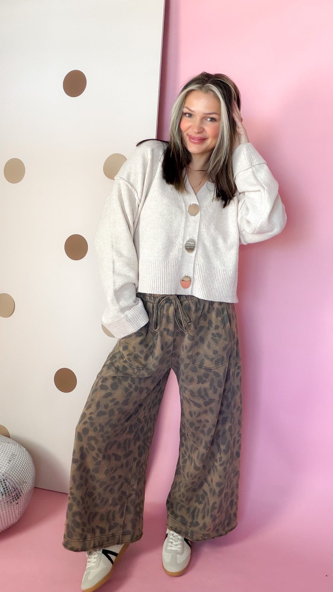 Front view of Easel mocha leopard terry knit pants styled with a cream cardigan and low-top sneakers.