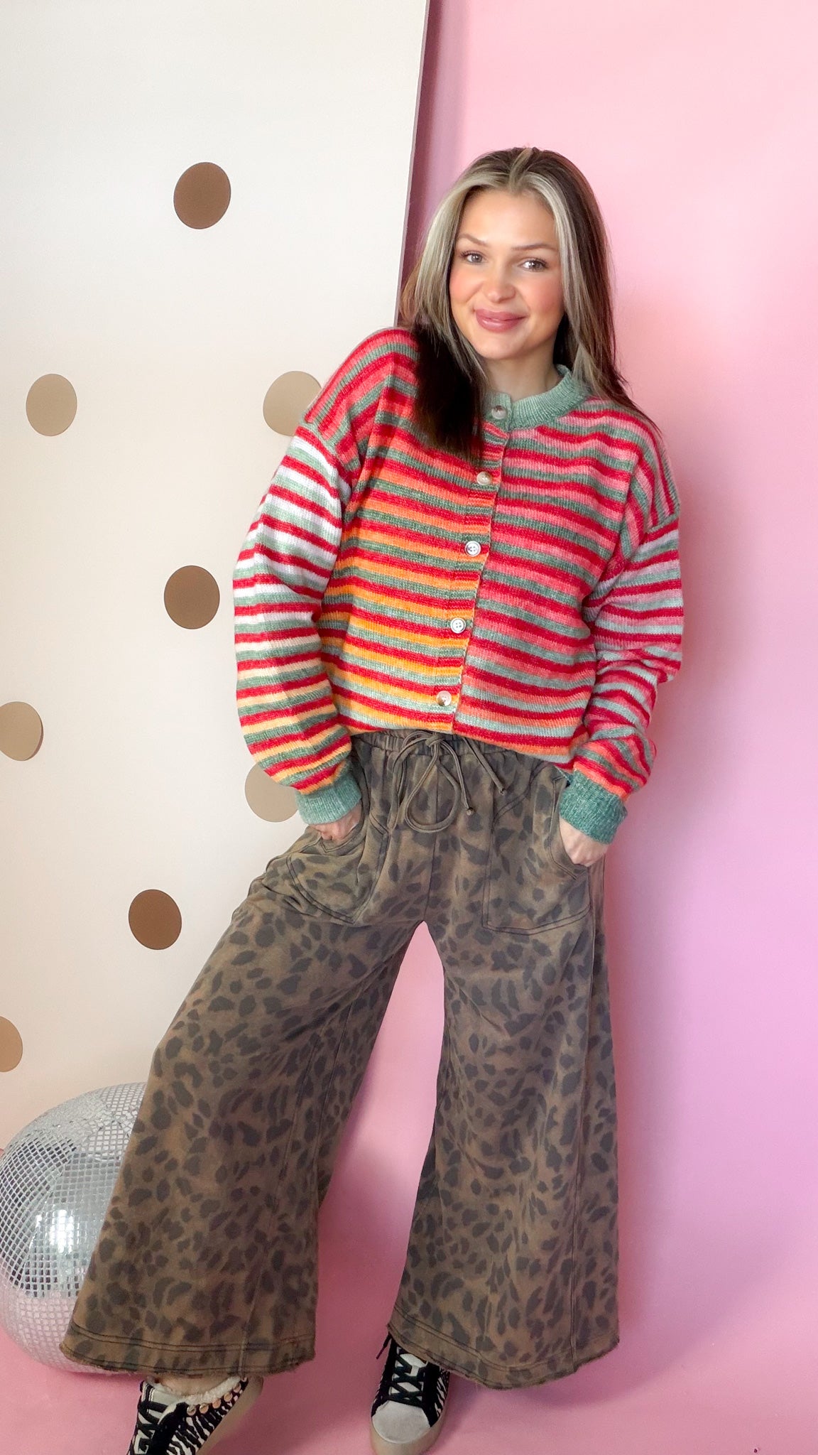 Women's colorful striped Christmas cardigan buttoned up with leopard print pants and black sneakers