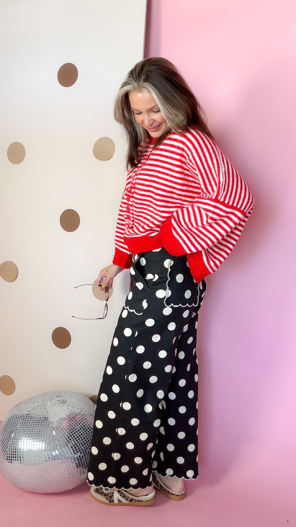 Side view of black polka dot pants showing wide legs, scalloped hems and scalloped back pocket trim.