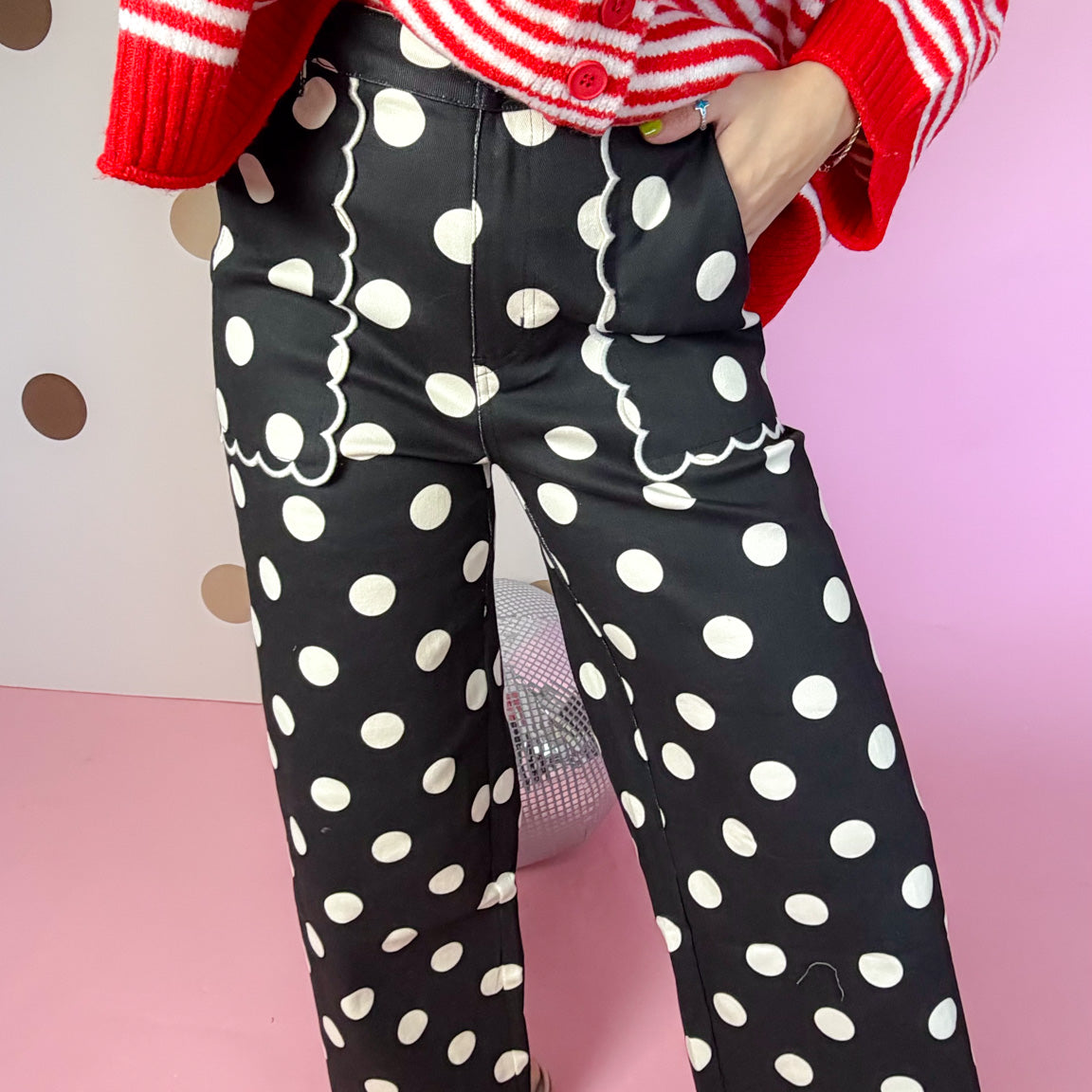 Close-up of black polka dot pants showing scalloped front pockets, wide legs and scalloped hems.