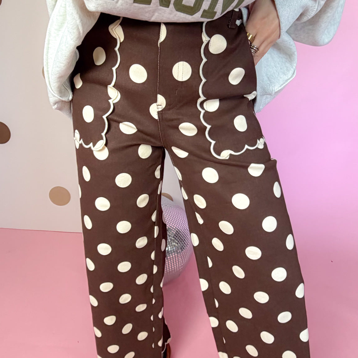Detail of brown polka dot pants showing scalloped front pocket trim, wide legs and scalloped hems.