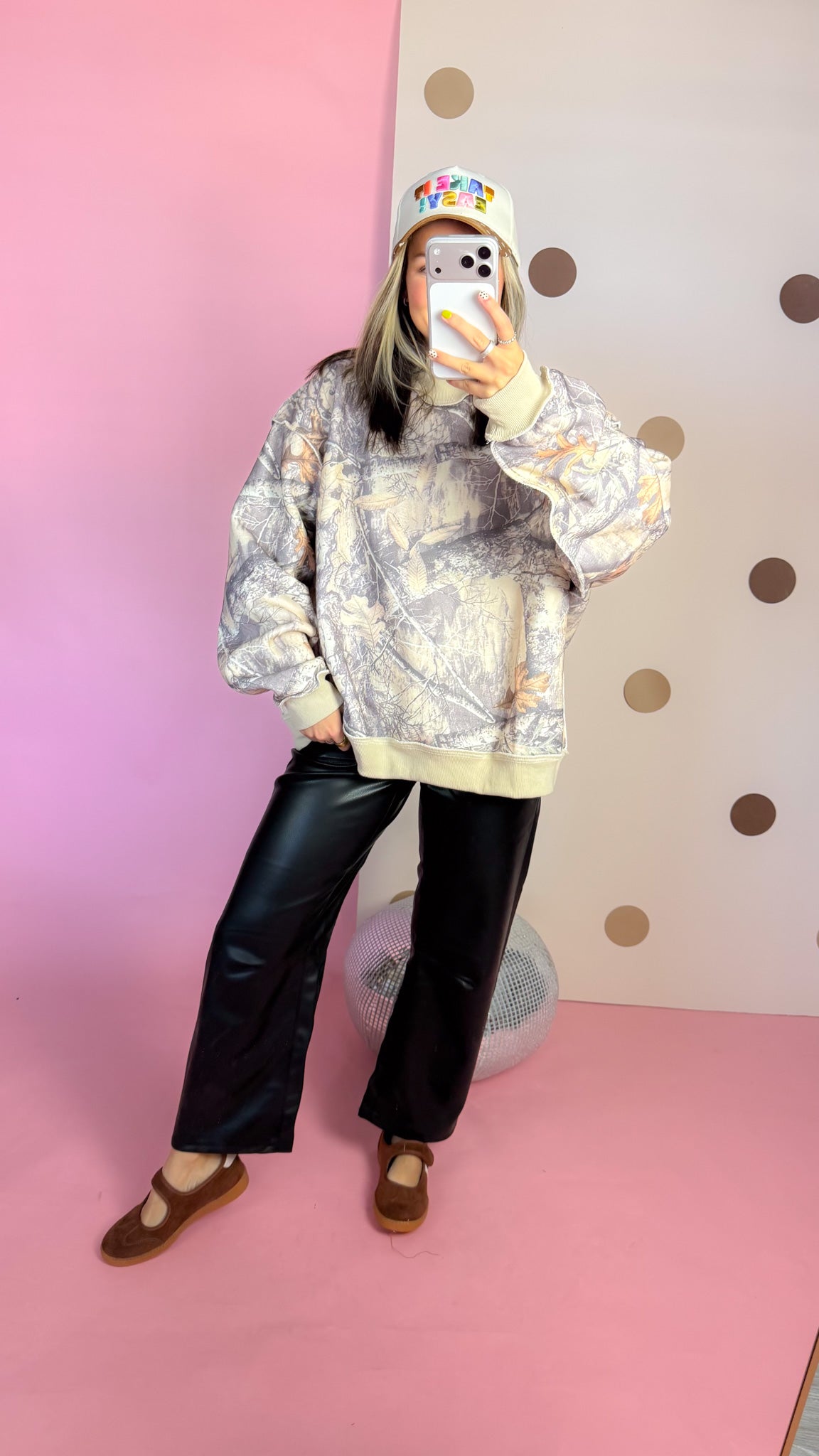 Mirror outfit view of taupe camouflage mock neck sweatshirt with black wide-leg pants and brown flats.