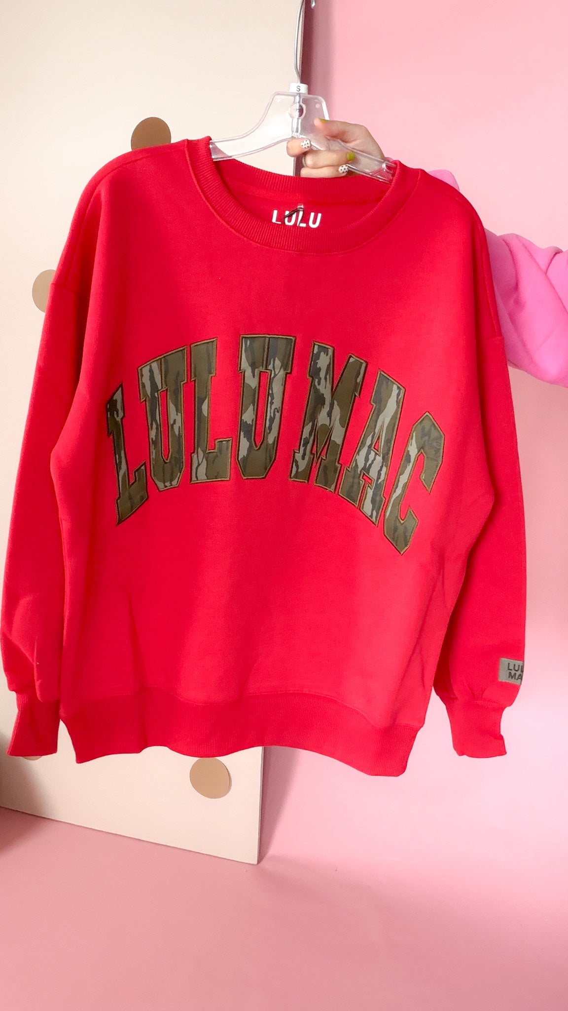 Front of red Lulu Mac crewneck sweatshirt with large arched Bottomland camo lettering, ribbed trim, and sleeve logo patch.