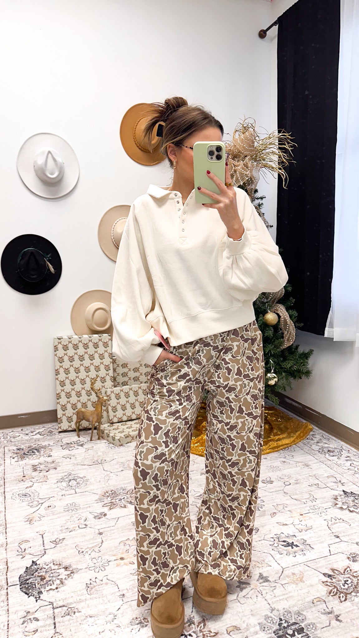 Person wearing a white blouse and patterned pants in a room with decorative items.
