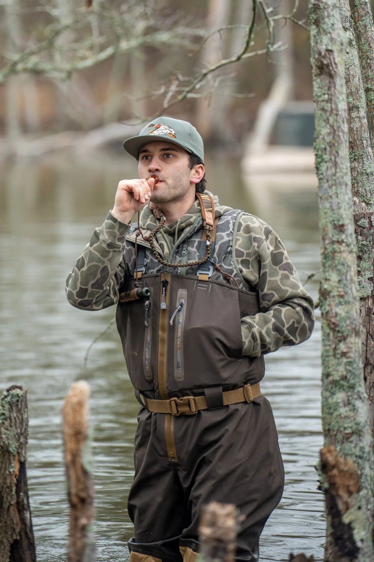 Local Boy duck down vest in camo worn over waders by hunter calling ducks in flooded timber