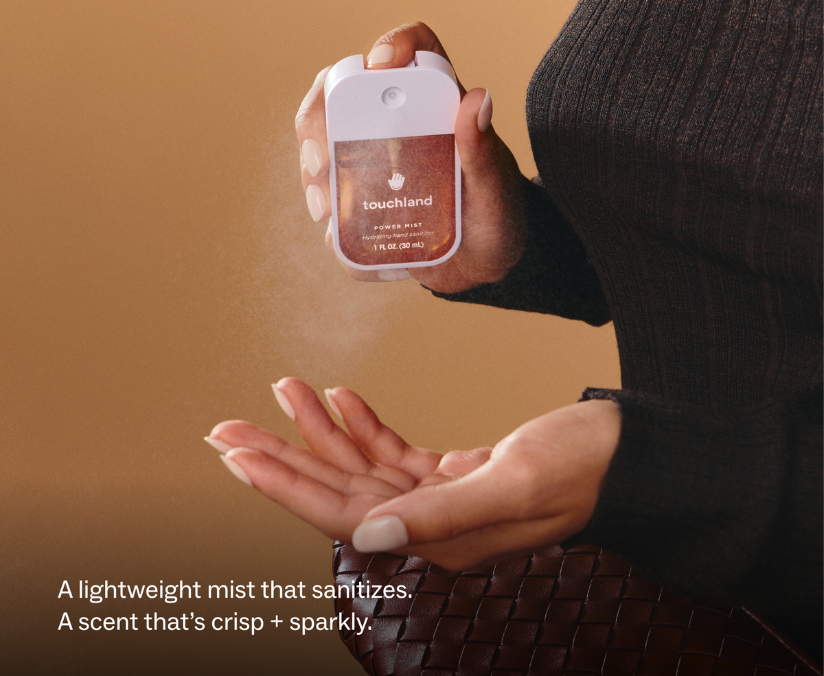 Touchland Spiced Pumpkin-Tini Power Mist being sprayed onto a hand, dark coat