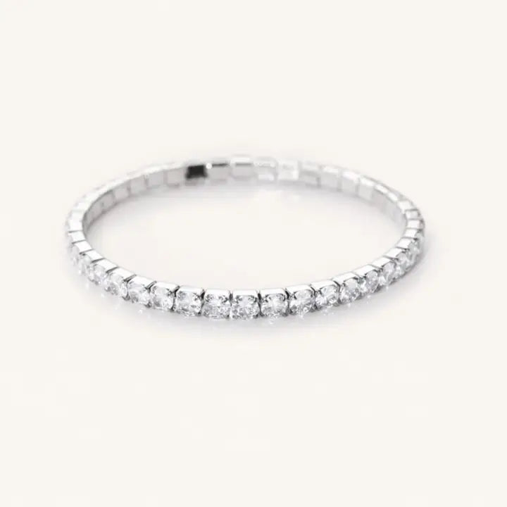 Angled view of a silver-tone tennis bracelet showing clear round stones and the sides of their settings.