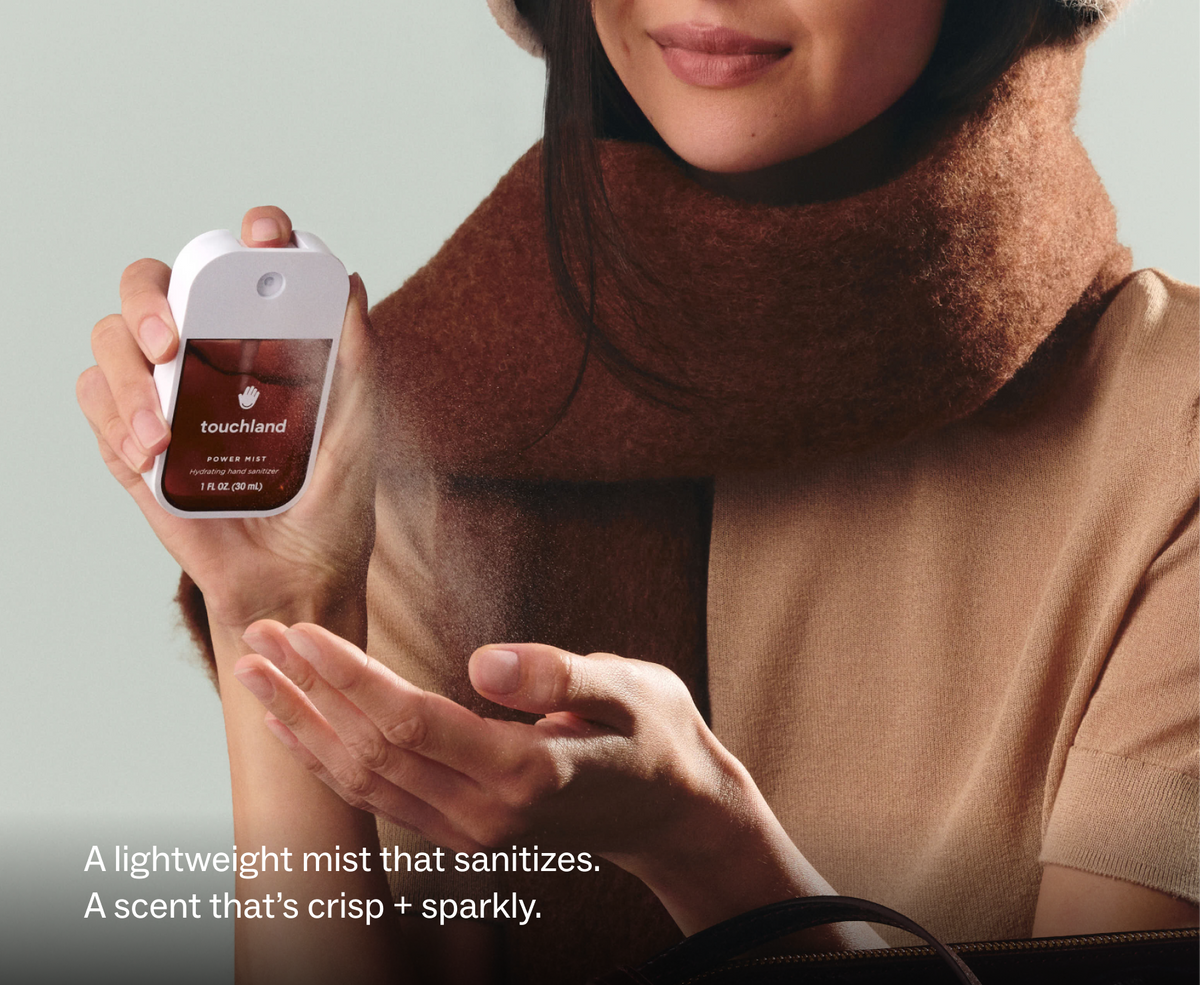 Touchland Salted Caramel Power Mist being sprayed onto a hand, brown scarf