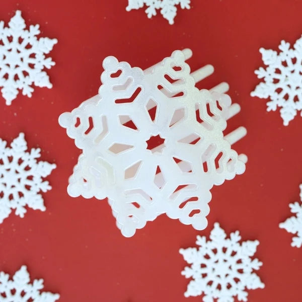 Teleties white glitter snowflake hair clip on a red background with paper snowflakes