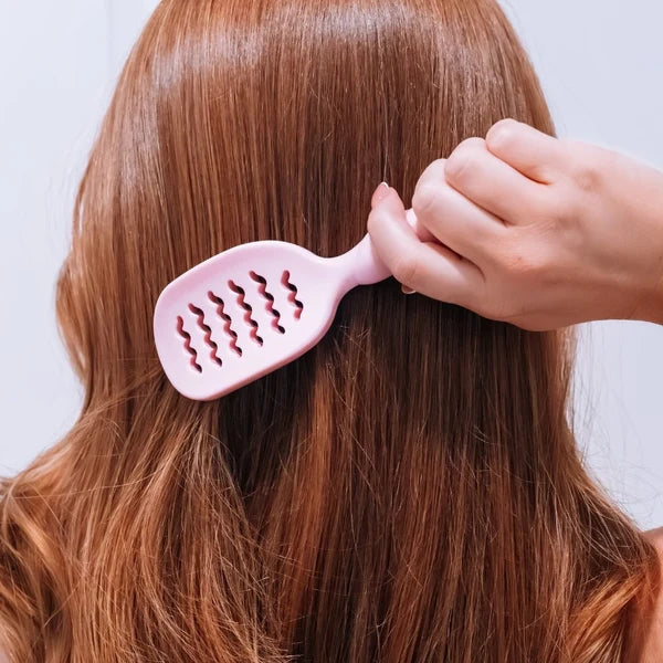 Woman brushing long red hair with the Teleties Mini Vented Brush in Bubblegum Pink