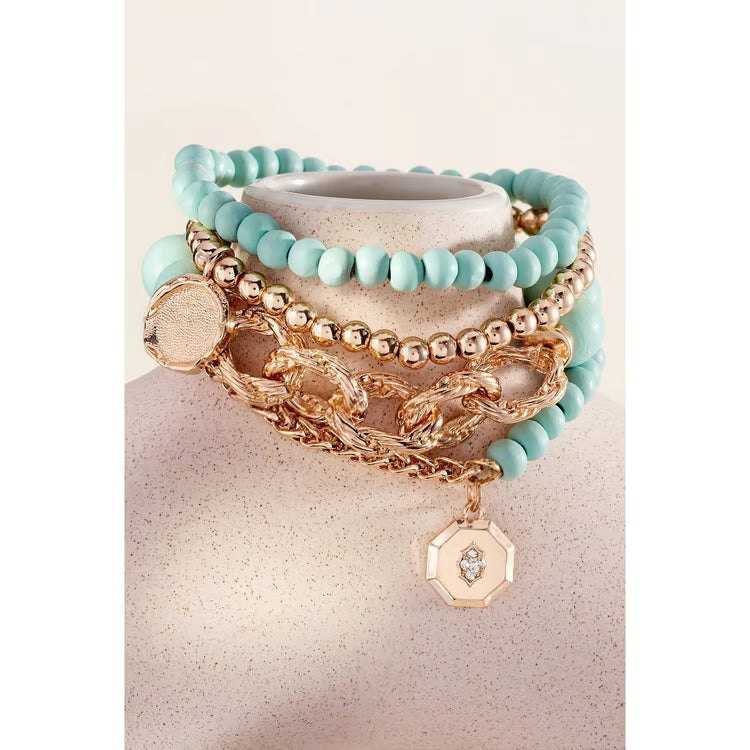 Charlie Paige Mayan teal bracelet set stacked on a stand, teal beads mixed with gold chain and charm