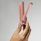 Hand opening a terracotta Kitsch Hair Volumizing Clip to show the comb teeth