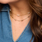 Marina freshwater pearl necklace worn with a longer gold-tone necklace and an open-neck denim shirt.