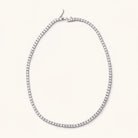 Silver-tone Gigi tennis necklace with a continuous row of cubic zirconia gems and clasp on a light background.