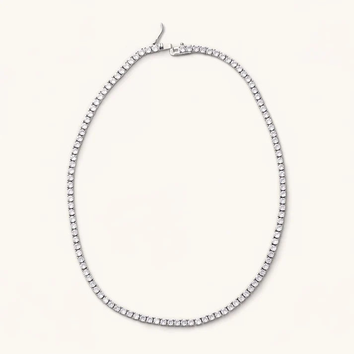 Silver-tone Gigi tennis necklace with a continuous row of cubic zirconia gems and clasp on a light background.