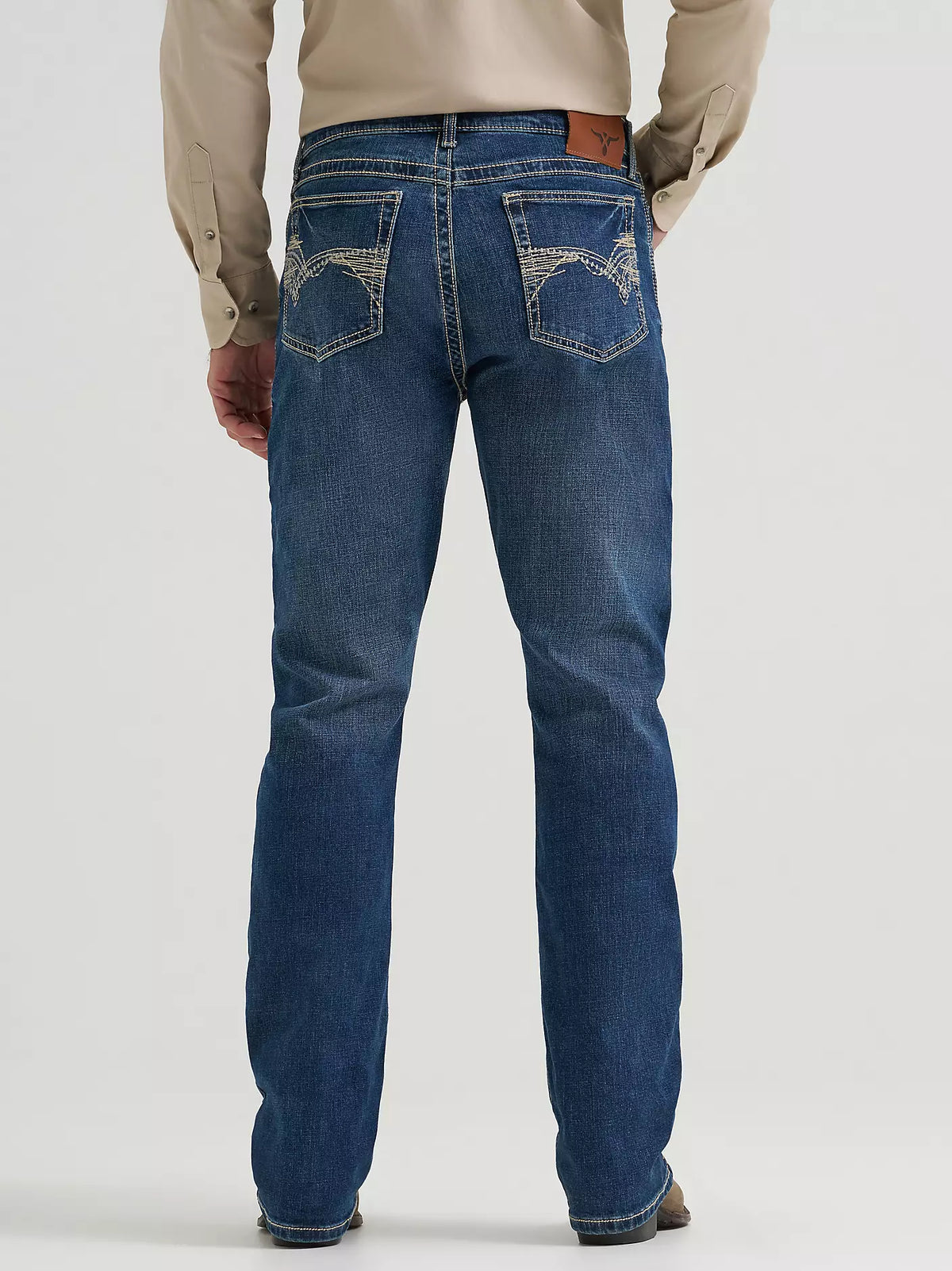 Man wearing blue jeans standing against a plain background