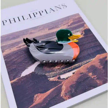 A duck-shaped hair clip or hair accessory with a glossy black, gray, green, orange, and yellow design.