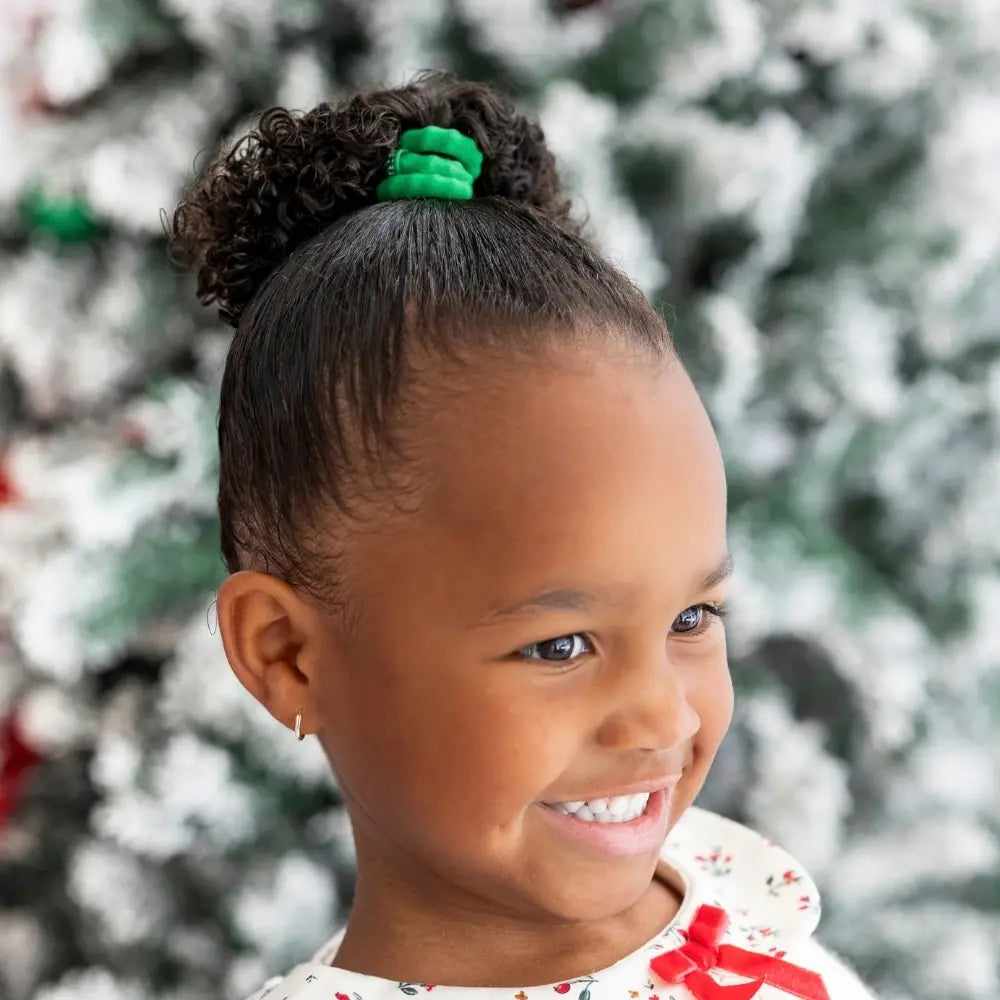 Smiling girl wearing a green Teleties Jolly & Bright Small Nylon Hair Tie in a top bun