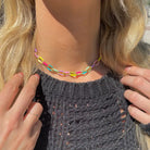 Pippa multicolor paperclip chain necklace worn close to the neck above a dark gray knit top.