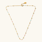 Phoebe gold-tone ball necklace with tiny multicolored beads and an extender, laid flat on a light background.