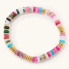 Julia multicolor beaded stretch bracelet with pink, blue, green and pale beads and gold accents on a light background.
